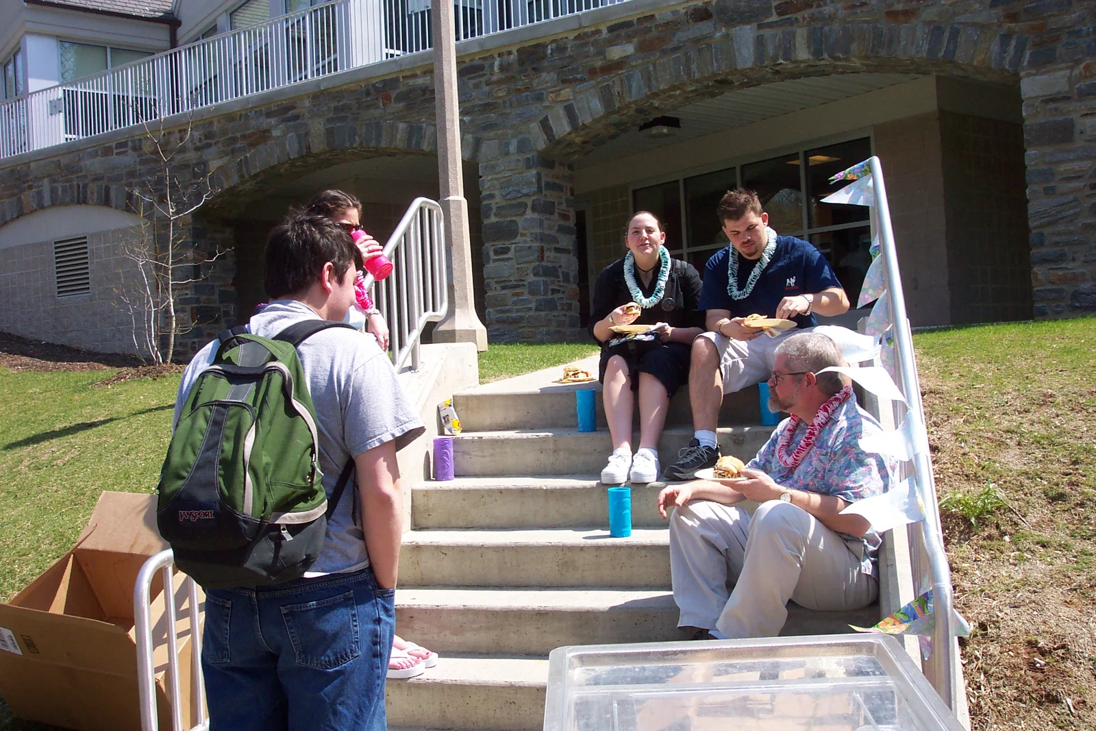 A few students and Professor Bryan Polk chat on the steps to the basement entrance of Lares.
