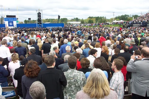 The graduates process in, obscured from view by the crowd. 
