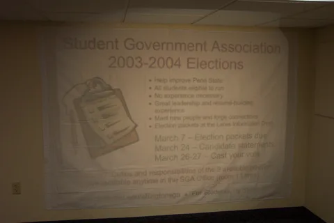Next, the banner is hung on the wall, with the projector displaying the design on top of the sheet.