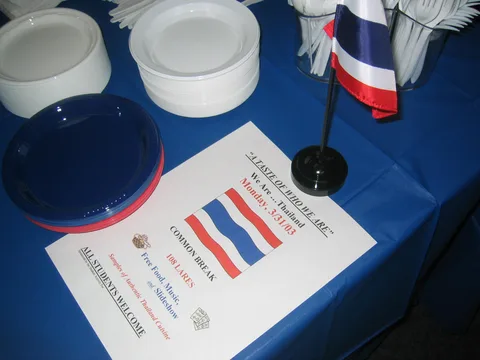 Plates and the flag of Thailand line a table.