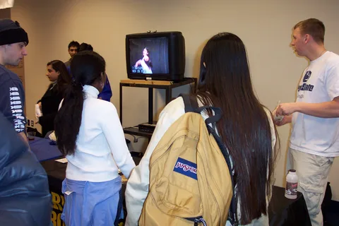 Students watch a TV showing a performance of one organization's members. 