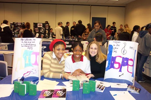 Again, Amy Frizell, Adrianna Simon, and another woman staff the Praise and Gospel Association table. 
