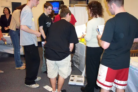 A few students congregate around a health provider's table.