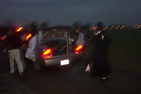 This slightly blurred image shows the speaker system setup in the back of the car, covered in coats and other paraphenelia. 