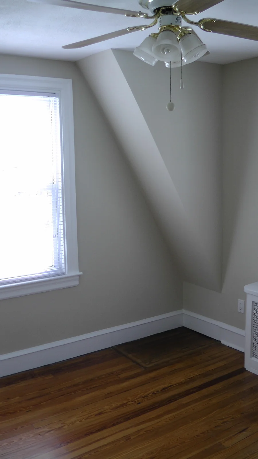 This second bedroom contains two bright windows, a ceiling fan, and ample space for a bed and several other pieces of furniture.