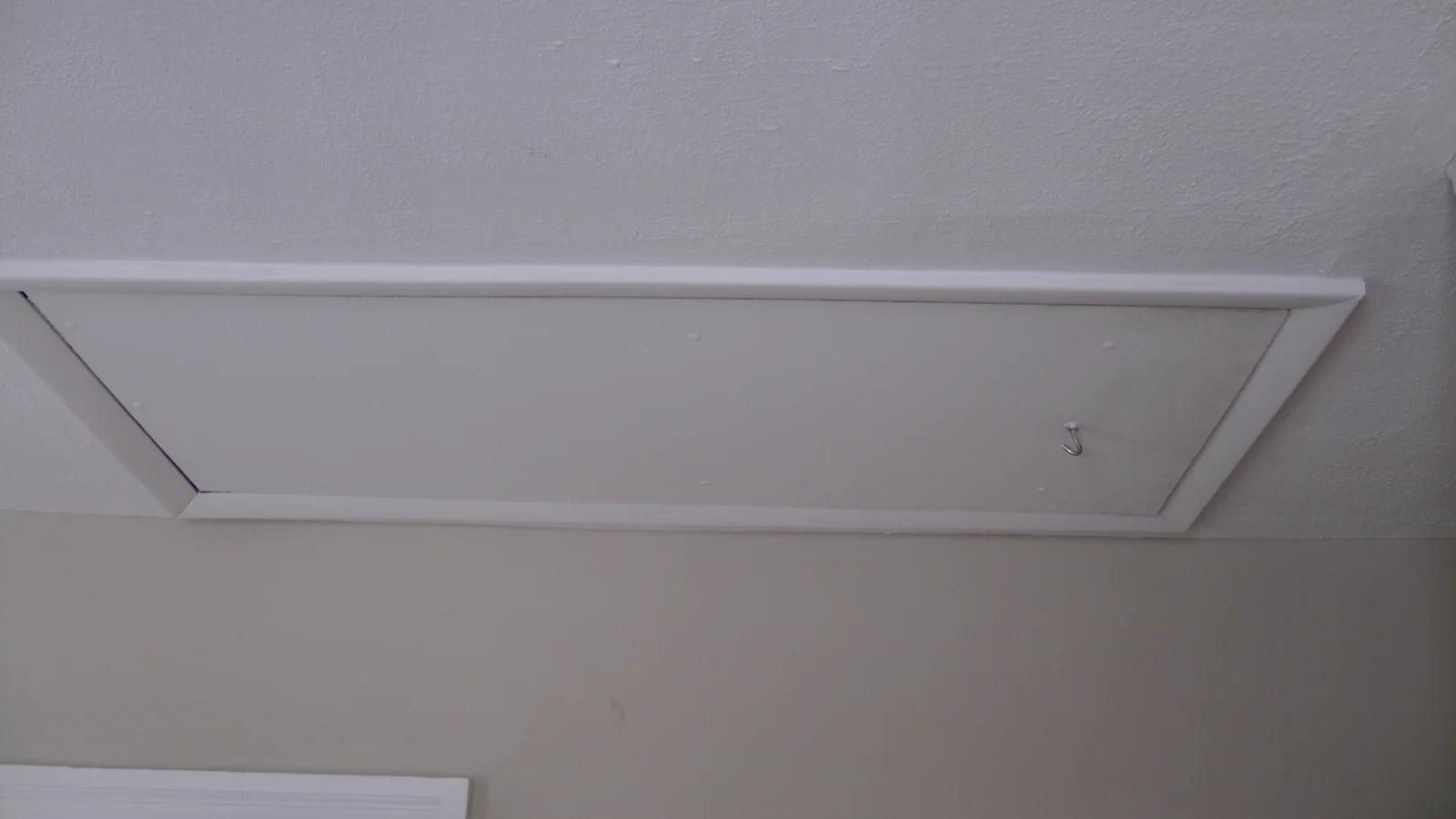 This access panel exposes a ladder into the unfinished attic, which can be used for storage or left unoccupied.