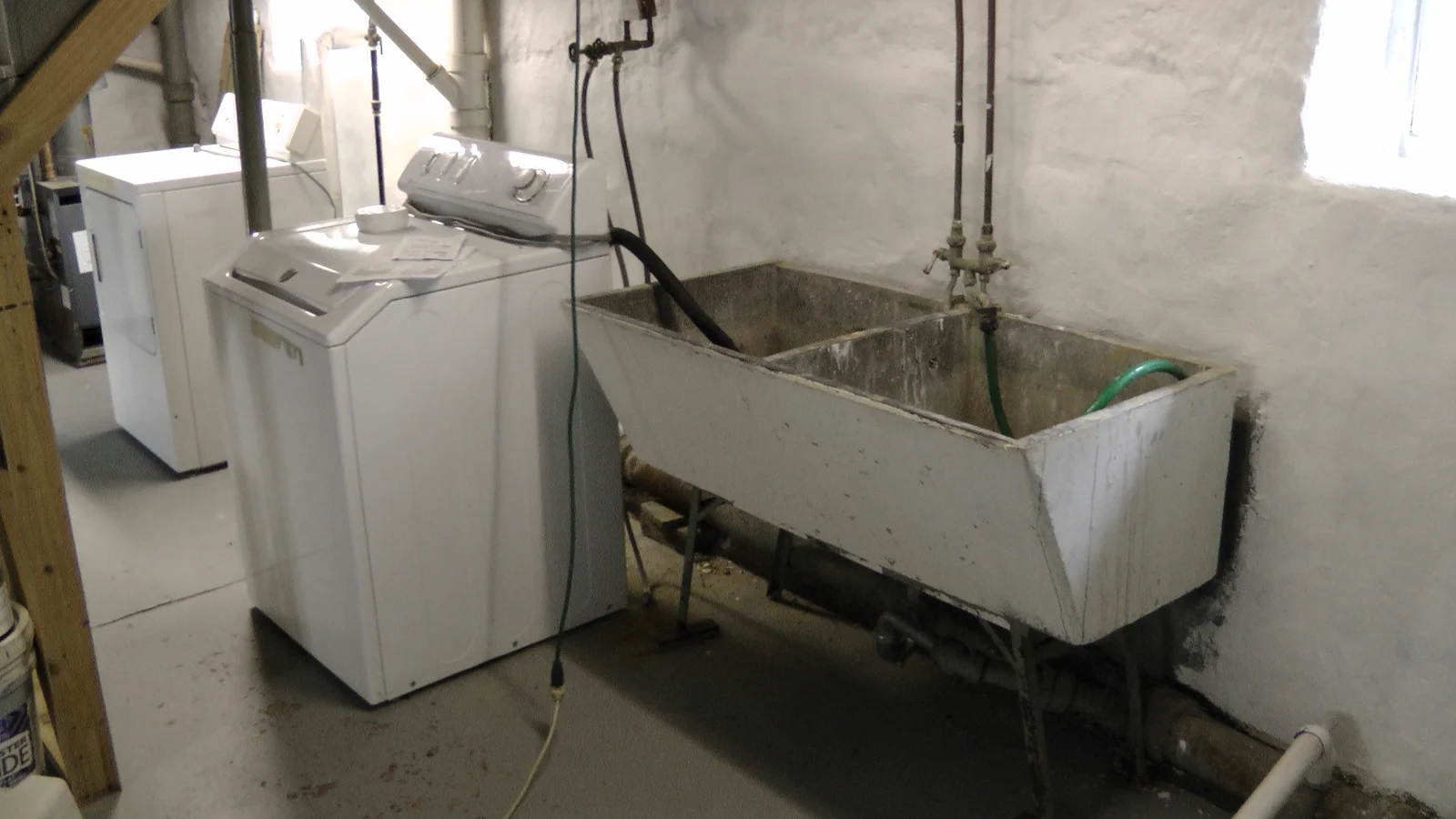 A closer shot of the basement sink and the laundry appliances.