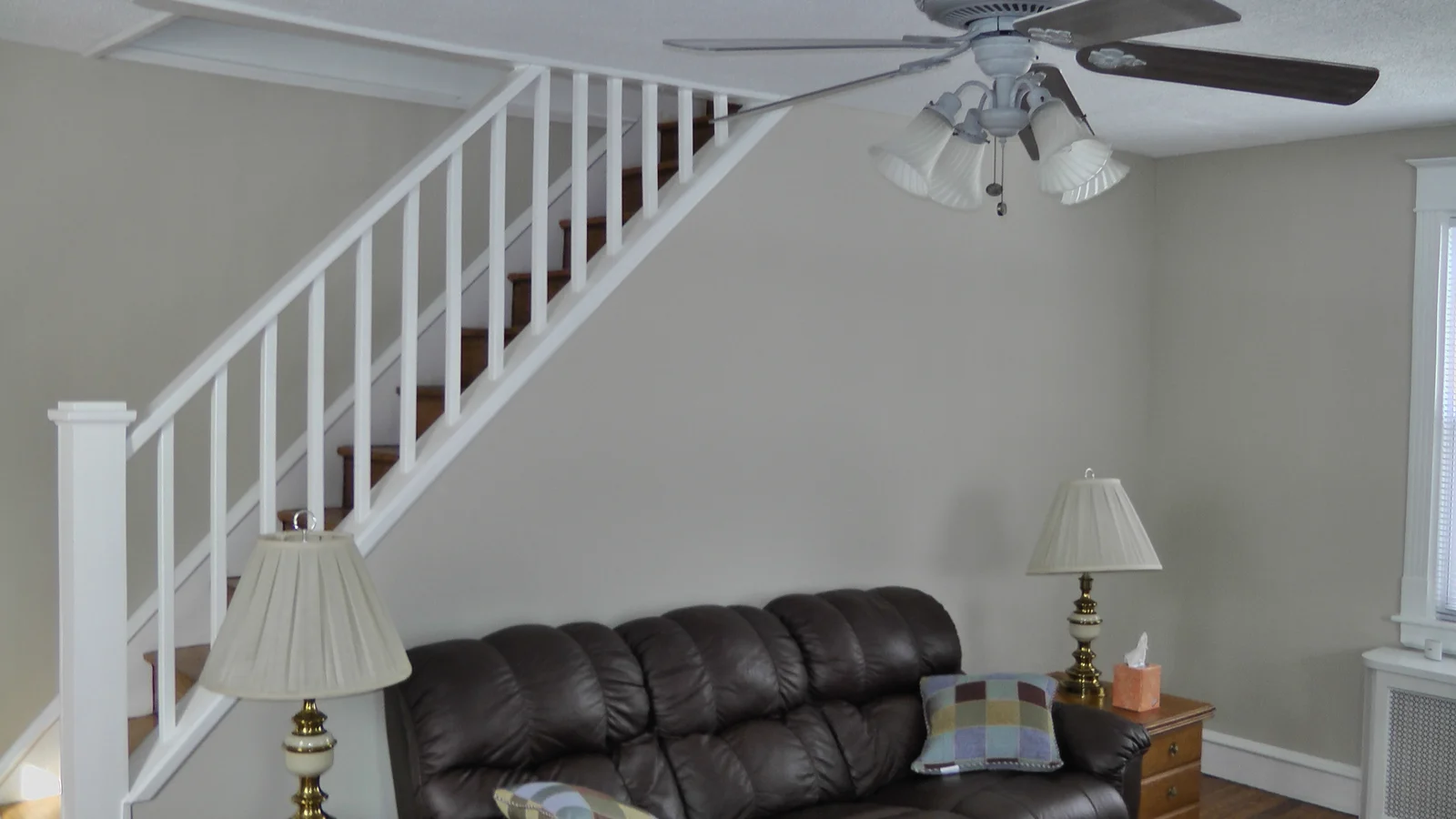 An upper shot of the living room, displaying the ceiling fan and freshly painted walls and ceiling.