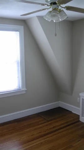 This second bedroom contains two bright windows, a ceiling fan, and ample space for a bed and several other pieces of furniture.