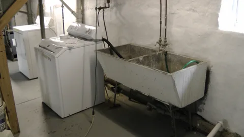 A closer shot of the basement sink and the laundry appliances.