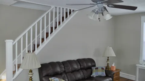 An upper shot of the living room, displaying the ceiling fan and freshly painted walls and ceiling.